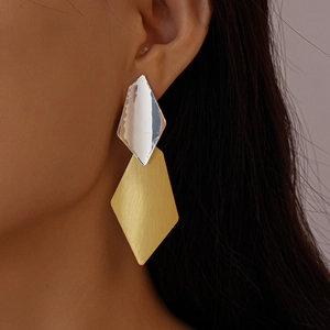 Close-up of geometric two-tone earrings with silver and brushed gold metal finish