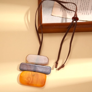 Detail of geometric resin pendant featuring colorful block layers on a soft suede cord