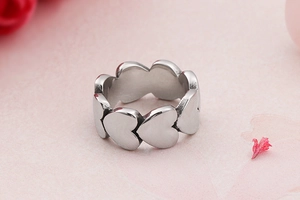 Macro shot of silver intertwined heart ring with hollow design on pink background