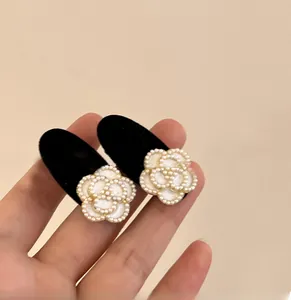 Detailed close-up of a pair of black velvet camellia flower hair clips with small pearls