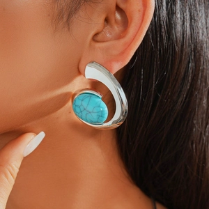 Close-up of a silver-tone C-shaped earring with a marbled turquoise stone inlay on model