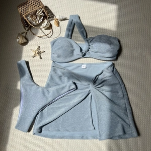 Close-up of light blue glitter bikini set with matching sarong and beach accessories