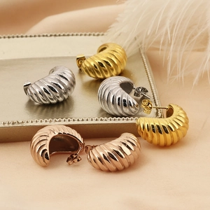 Detailed view of three pairs of spiral textured C-shape earrings in gold silver and rose gold