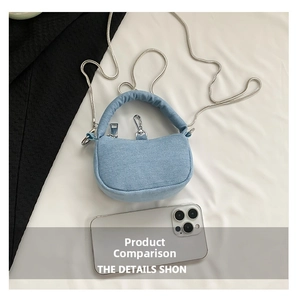 Macro detail of mini light blue denim bag with silver chain next to a white smartphone
