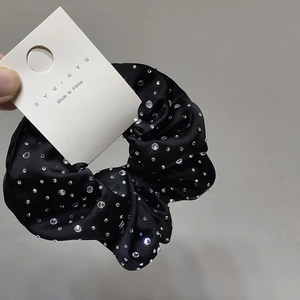 Detail of black satin hair scrunchie with sparkling crystals and brand tag