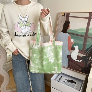 Dettaglio della borsa tote in tela tie-dye verde e bianca con motivi artistici a inchiostro