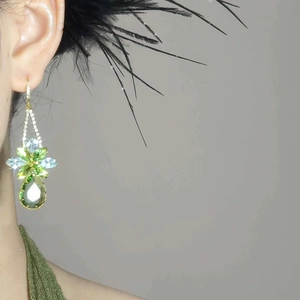 Close-up of luxury butterfly drop earrings with green teardrop gemstones on a model