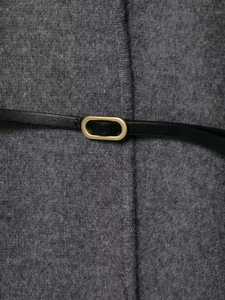 Detail of wool coat featuring a slim black leather belt with a matte gold oval buckle