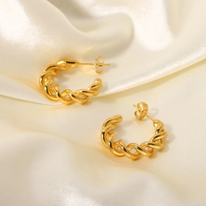 Macro shot of 18K gold-plated C-shaped earrings with twisted rope texture on silk
