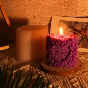 Detail of purple rose pillar candle with Love engraving on a wooden base