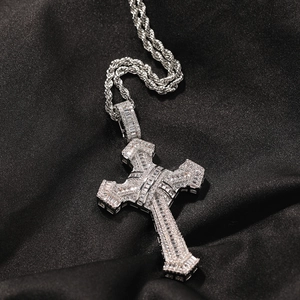 Macro shot of silver hip-hop cross pendant with clear cubic zirconia on black silk