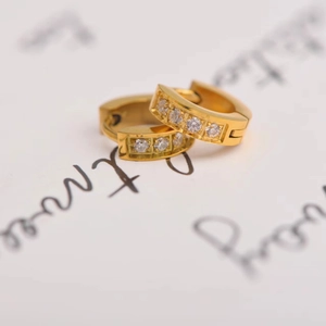 Macro view of gold hoop earrings with channel-set cubic zirconia on decorative paper