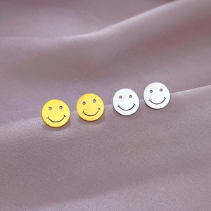 Minimalist smiley face stud earrings in gold and silver finish on purple silk fabric