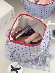 Detail of light blue quilted makeup bag with red hearts showing large inner capacity