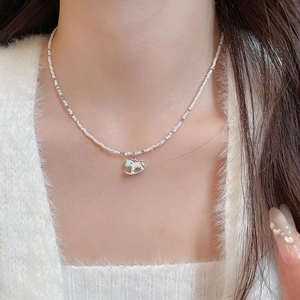 Détail du collier de perles avec pendentif cheval à bascule bleu clair sur le cou