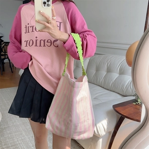 Detail of green ruched handle and pink striped canvas tote bag in a mirror selfie