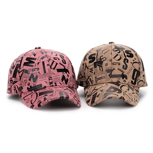 Close-up of pink and khaki baseball caps with all-over digital letter newspaper print