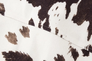 Close-up of brown and white cow print fabric with fine stitching and soft texture