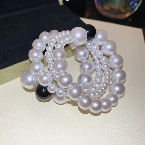 Detailed close-up of multi-layer pearl bracelet with black and white beads on beige background