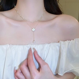 Detail of double-layer necklace with camellia pendant and pearls on elegant model
