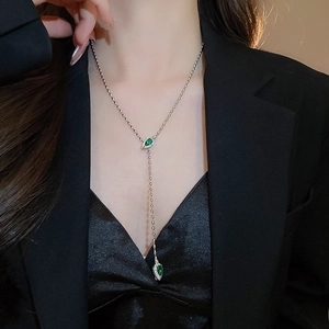 Detail of Y-shaped silver beaded necklace with green drop pendants and zircon accents