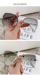 Detail of rimless oversized sunglasses with gold metal frame and green gradient lenses