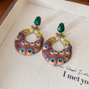 Gros plan de boucles d'oreilles paon vintage avec perles de résine vert goutte