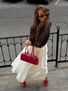 Close-up of a long white pleated maxi skirt blowing in the wind during a city street walk