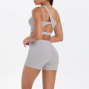 Detail of light grey asymmetric yoga set featuring cutout sports bra and high waist shorts