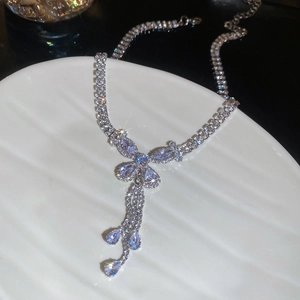 Close-up of silver necklace with zircon butterfly and teardrop pendant on a shell tray