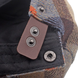 Detail of adjustable leather strap and metal snaps on British plaid wool blend beret hat