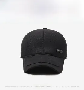 Detail view of black thermal baseball cap with ear flaps and side metal logo plaque