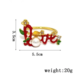 Detail of gold napkin ring featuring red Love text, a white pearl and crystal flowers