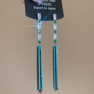 Macro detail of silver drop earrings with emerald zircon and chain tassels on display