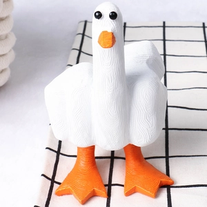 Macro view of a resin white duck figurine with orange beak on checkered fabric