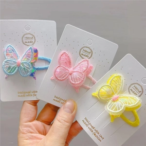 Detail of three embroidered butterfly hair clips with sequins and lace on display card