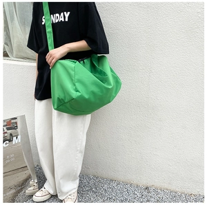 Detail of a bright green large capacity oxford crossbody bag worn in a street setting