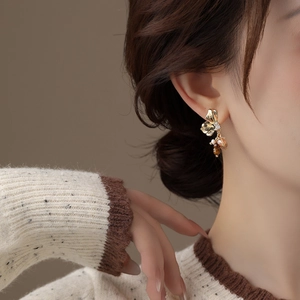 Close-up of vintage floral drop earrings with gold petals and tiger eye style beads on model