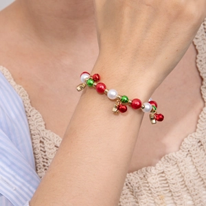 Nahaufnahme Weihnachtsarmband mit rot-grünen Perlen und goldenen Glöckchen am Handgelenk