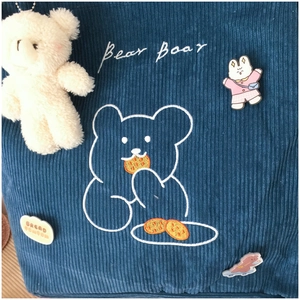 Detail of navy corduroy tote featuring cartoon bear embroidery and cute plush pendant