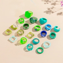 Flat lay of colorful resin rings in various shapes like heart and square with plant shadows