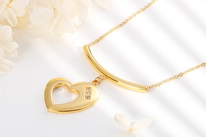 Detailed view of a gold heart pendant necklace featuring three small inlaid gemstones