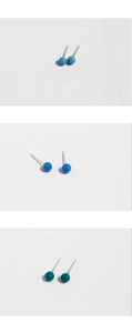 Detailed view of spherical enamel stud earrings in sky blue, royal blue and dark cyan