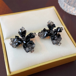 Vue latérale macro de boucles d'oreilles fleurs en cristal noir et gris en boîte