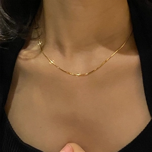 Detail of elegant 18K gold box chain necklace worn on neck for minimalist style