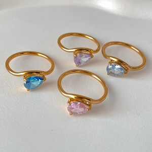 Close-up of four gold rings featuring pear-cut blue, purple, and pink gemstones