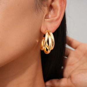 Close-up of golden triple-hoop earrings in high-gloss finish worn on the earlobe