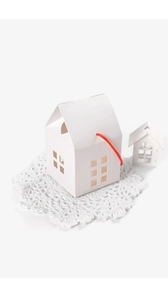 Close-up of white house-shaped paper gift box with hollow windows and a red string handle