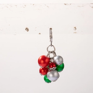 Close-up of Christmas earrings with vibrant red, green, and silver pearl pendants