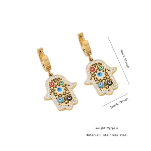Détail de boucles d'oreilles main de Fatma en acier doré avec breloques œil porte-bonheur
